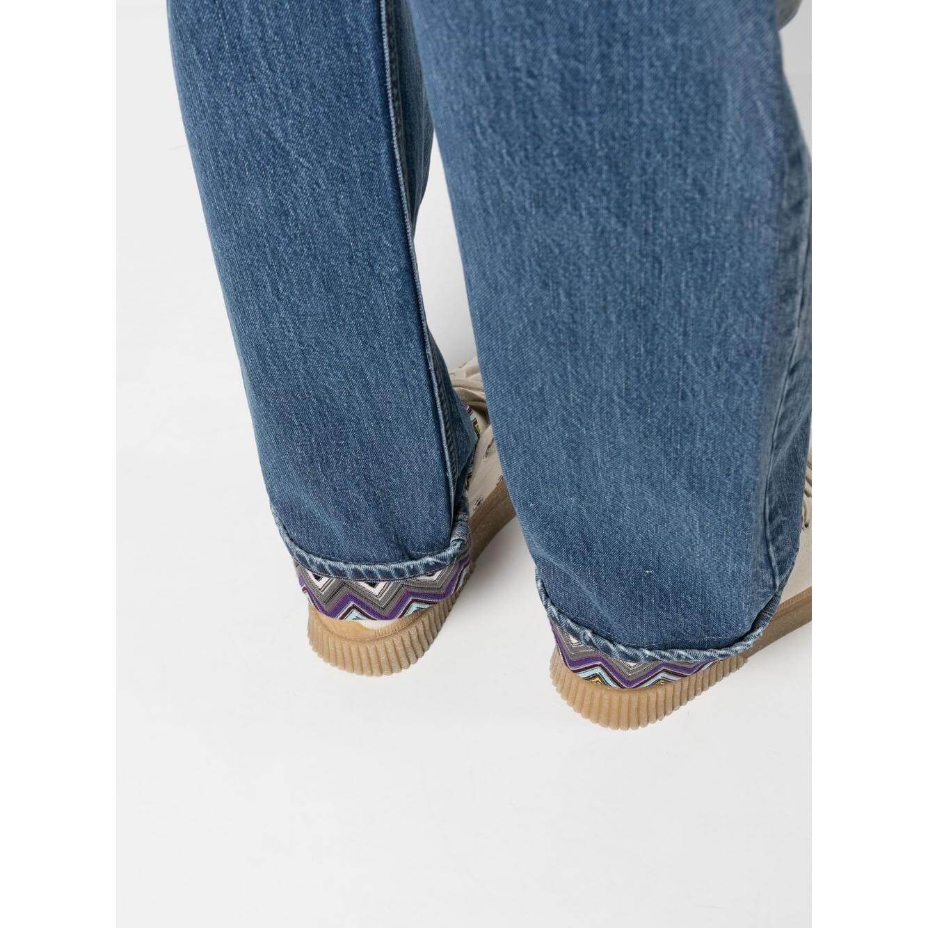 Close-up of Missoni stonewashed blue denim jeans with zigzag pattern cuffs.