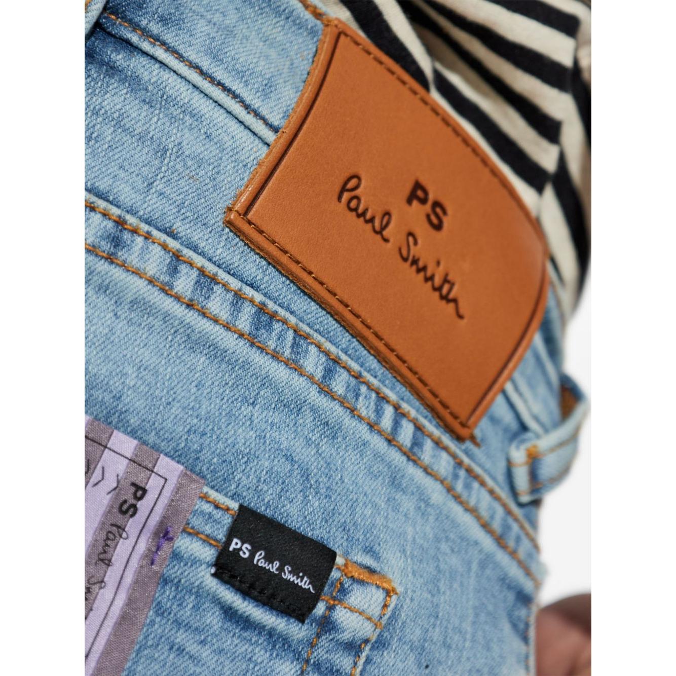 Close-up of PS By Paul Smith jeans showcasing leather brand patch and pocket tags on classic blue denim.