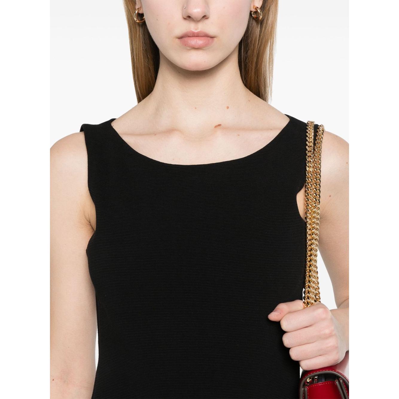 Model wearing Emporio Armani black ottoman jersey sheath dress with boat neck and gold chain strap handbag.