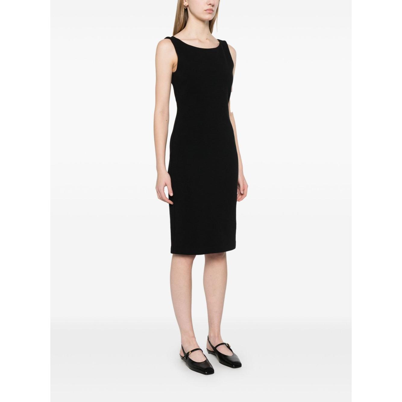 Woman wearing black Emporio Armani Ottoman Jersey Sheath Dress, sleeveless with boat neck and straight hem, standing in studio.