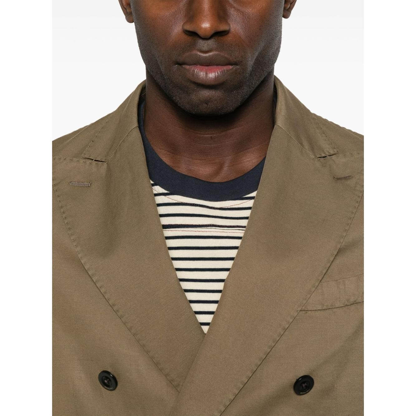 Man wearing a golden brown double-breasted linen Boglioli suit with black buttons and stripe shirt.