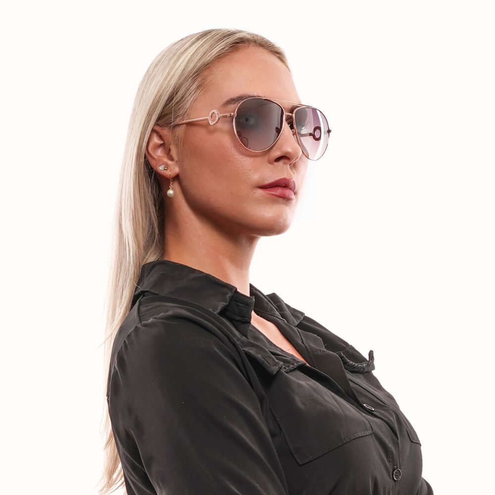 Woman wearing Guess rose gold aviator sunglasses with mirrored gradient lenses and metal frame.
