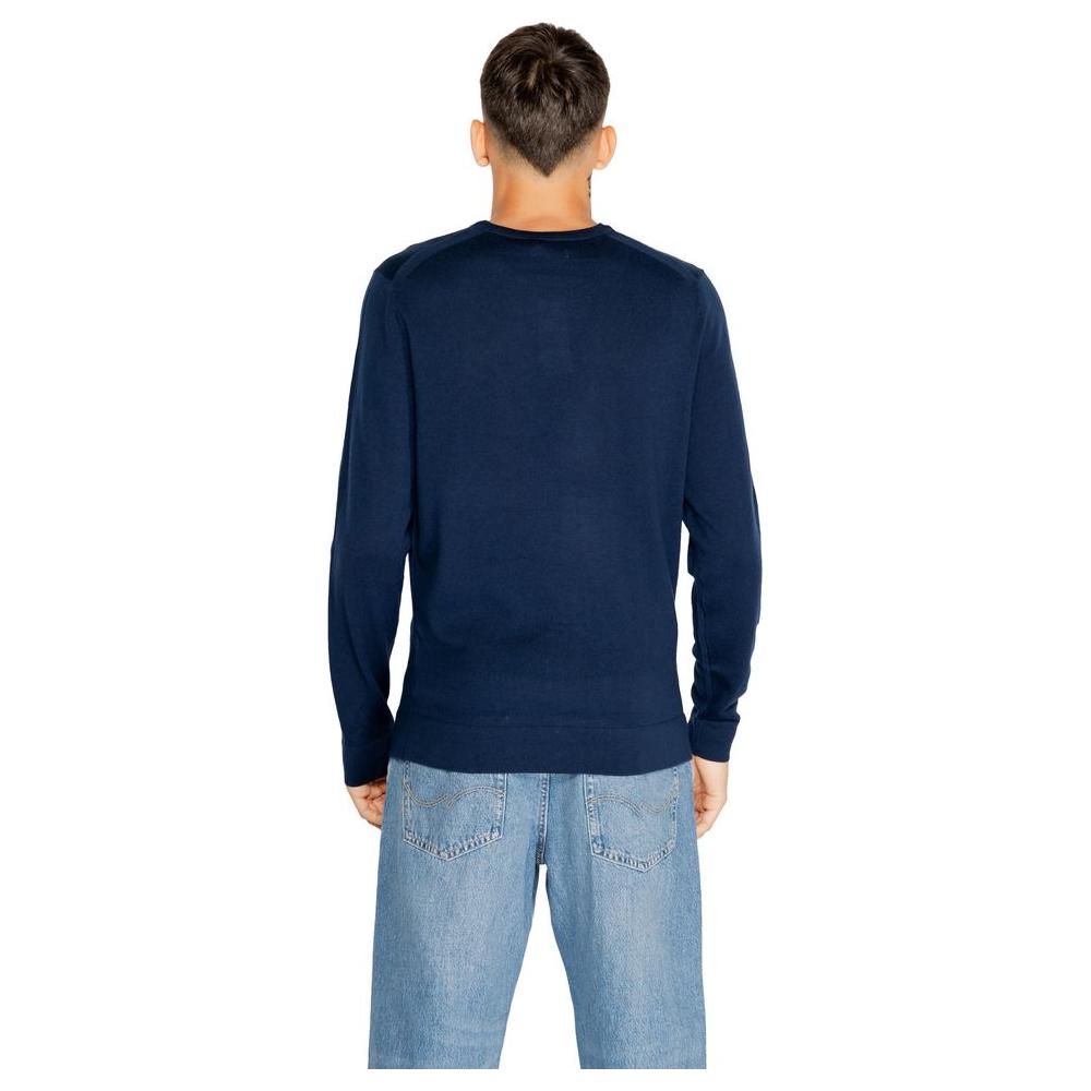 Back view of a man wearing a Calvin Klein blue recycled wool t-shirt from the men's knitwear Fall/Winter collection, paired with jeans.