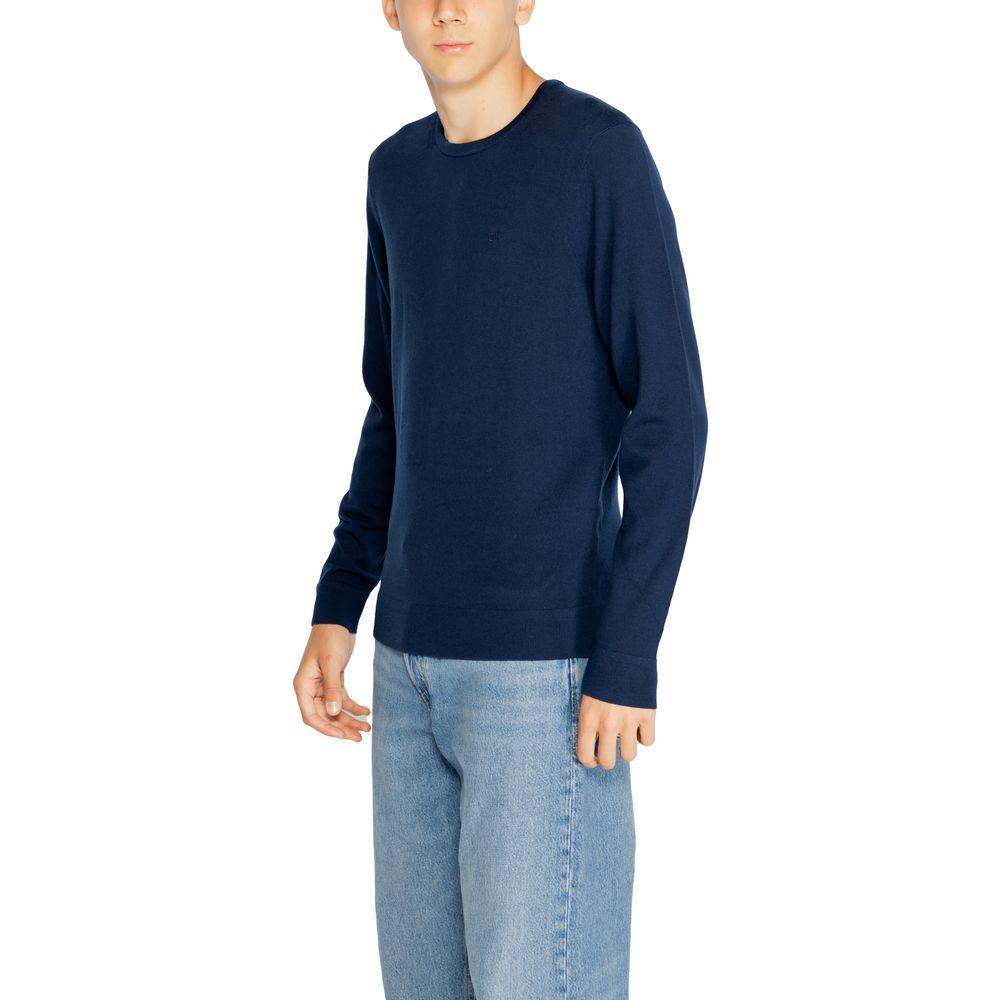 Man wearing Calvin Klein blue recycled wool t-shirt from the men's fall/winter knitwear collection.