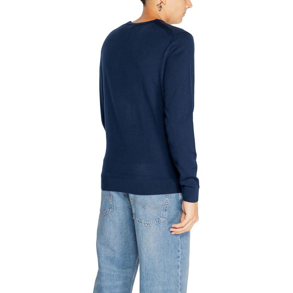 Back view of a person wearing a Calvin Klein blue recycled wool T-shirt, paired with light blue jeans, part of men's knitwear collection.