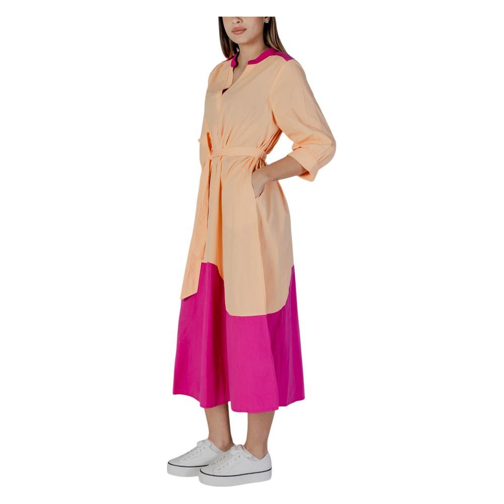 Two-tone peach and pink color-blocked dress with tie detail and white sneakers, part of a spring/summer women's collection.