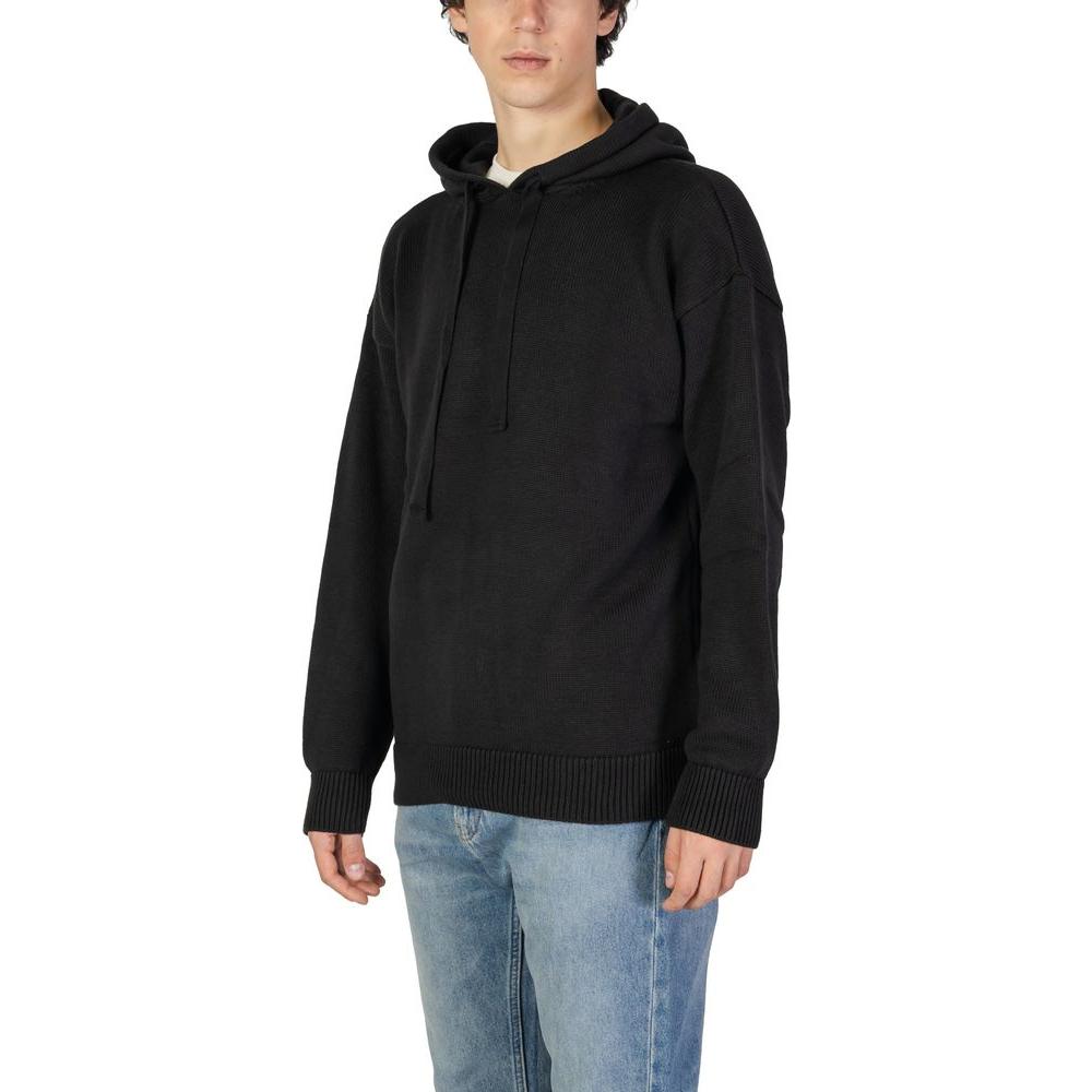 Model wearing Underclub black cotton sweater, men's knitwear for fall/winter, 50% cotton and 50% acrylic blend.