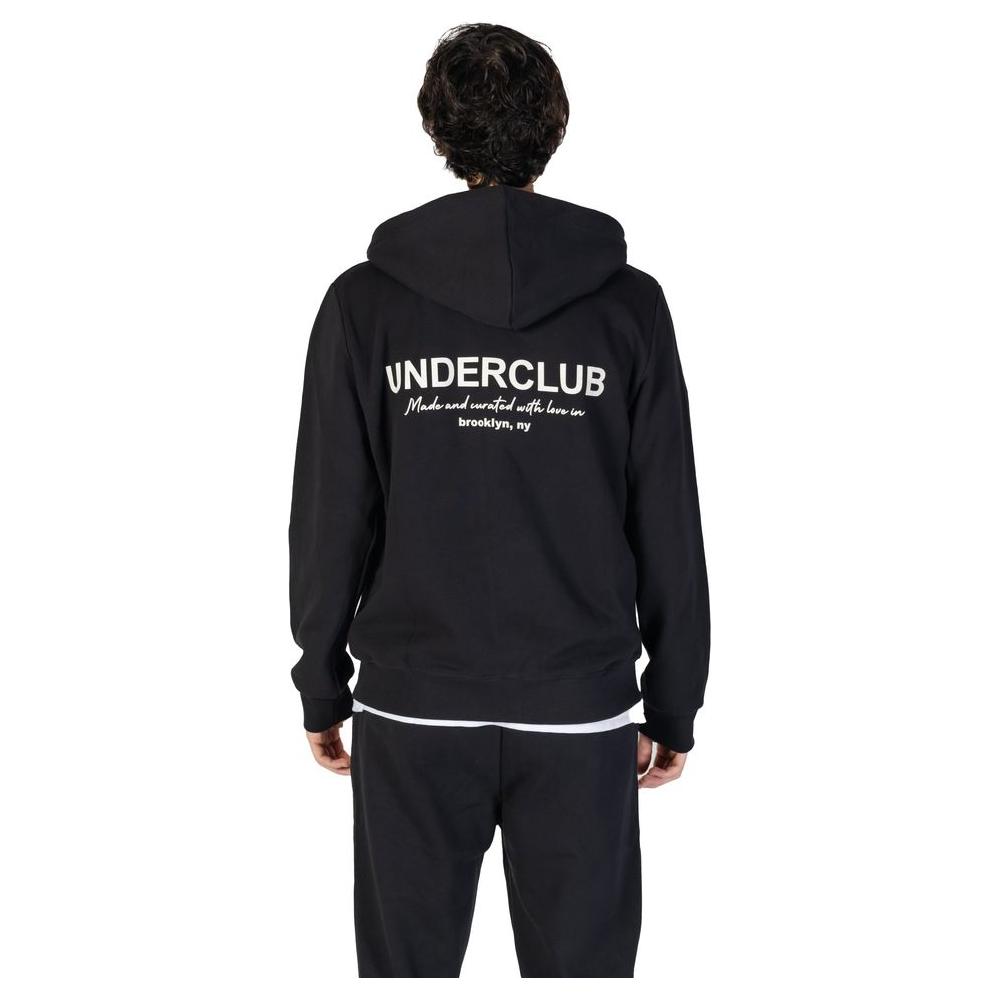 Rear view of a man wearing a black Underclub cotton hoodie from the men's fall/winter collection, featuring white text on the back.