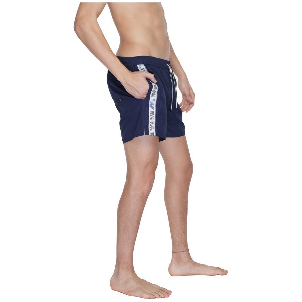 Side view of a model wearing blue Emporio Armani men's boxer swimwear, highlighting polyester fabric and branded details.