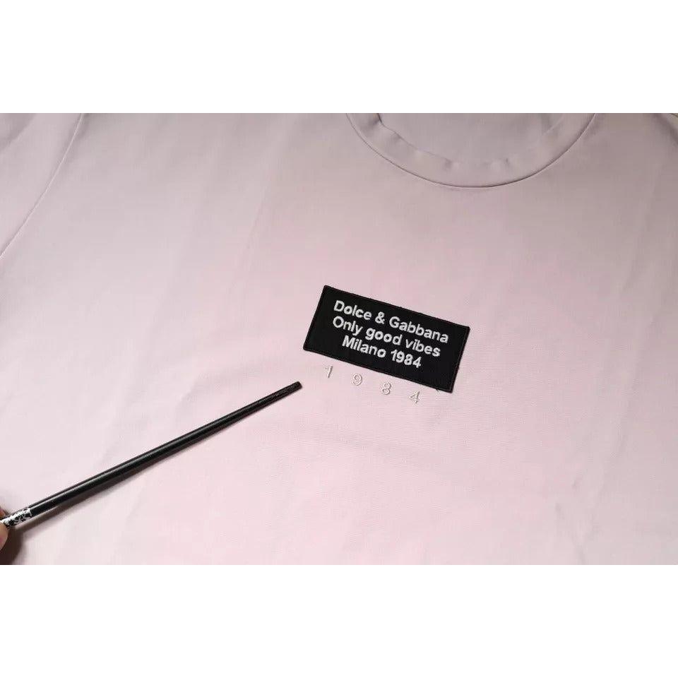 Close-up of Dolce & Gabbana beige logo crew neck t-shirt highlighting text 'Only Good Vibes Milano 1984' with pen pointing.