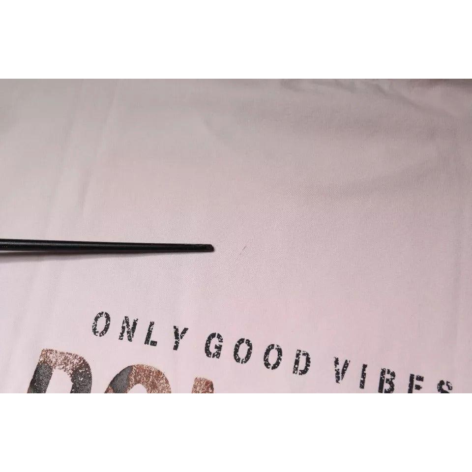 Close-up of Dolce & Gabbana beige t-shirt showing graphic print with text 'Only Good Vibes' and minor defect on fabric.