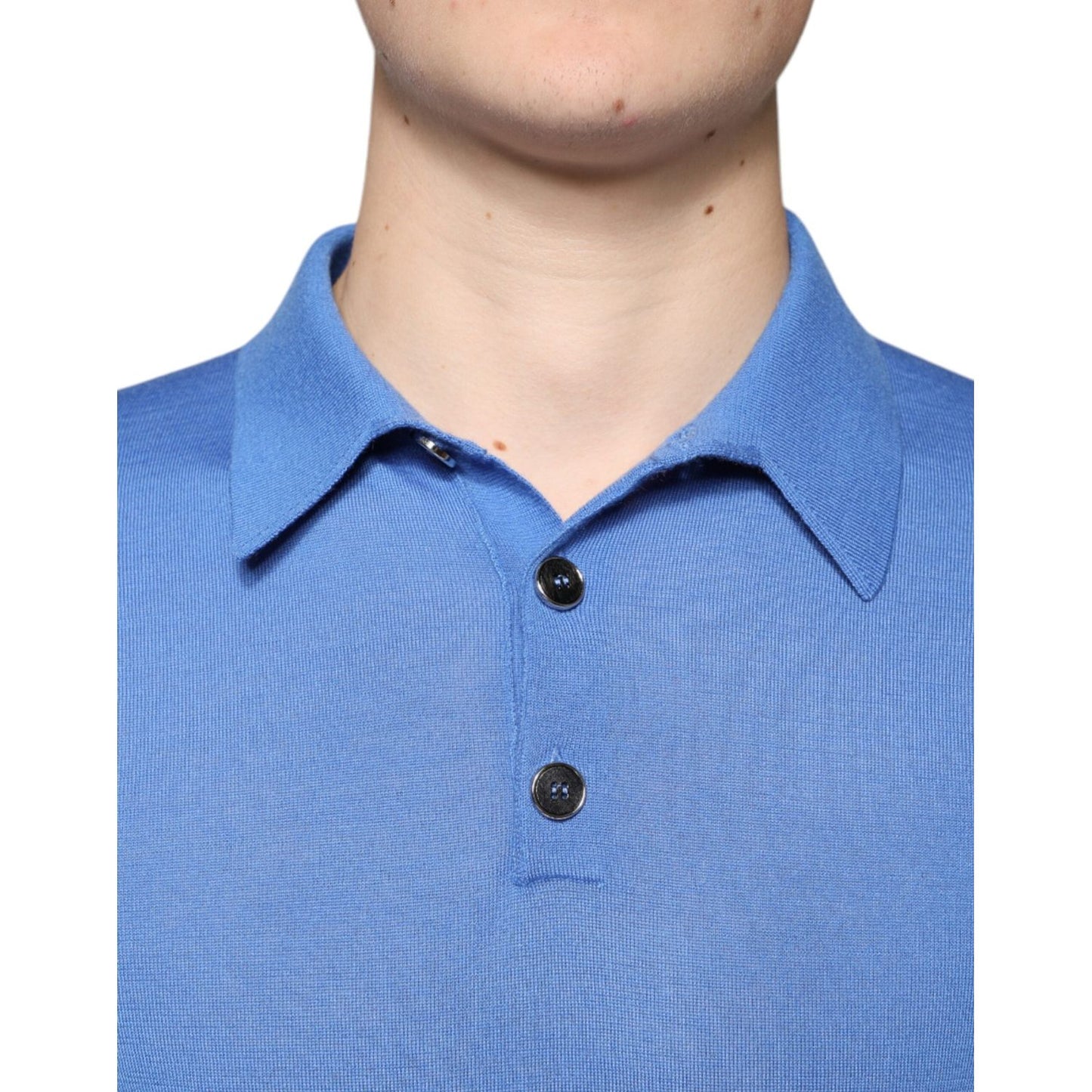 Close-up of blue Dolce & Gabbana cashmere polo shirt with collar and black button closure. Minor defects repaired on front.