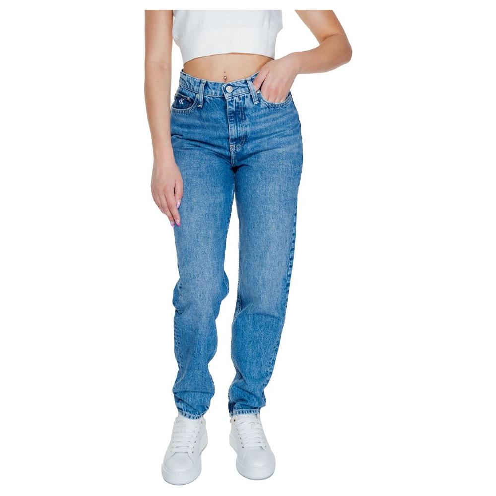 Woman wearing Calvin Klein blue mom jeans, cotton blend, from Autumn/Winter collection, standing with white sneakers.