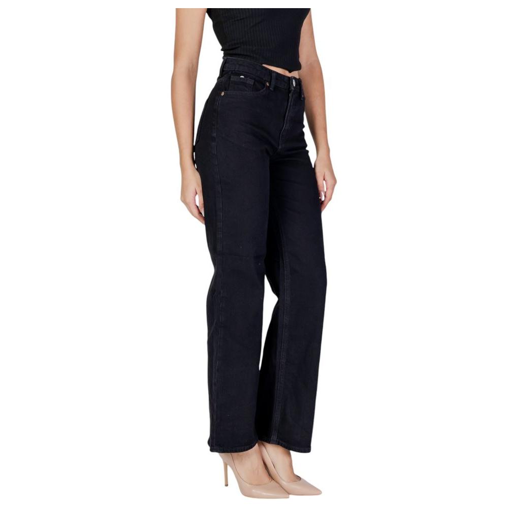 Woman wearing Vero Moda black cotton jeans, fall/winter collection, leg view, featuring 79% cotton and 20% recycled cotton.