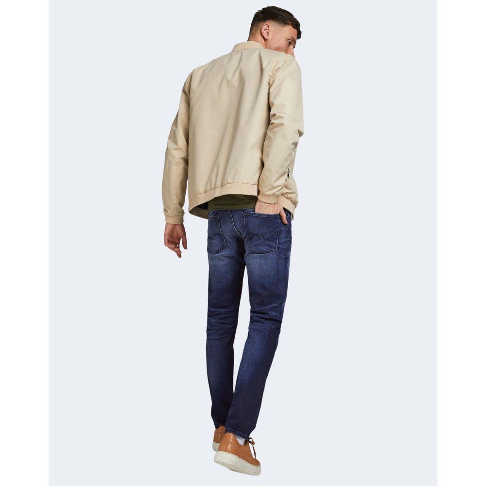 Man wearing Jack Jones blue cotton jeans with beige jacket, showcasing regular loose fit style from back view.