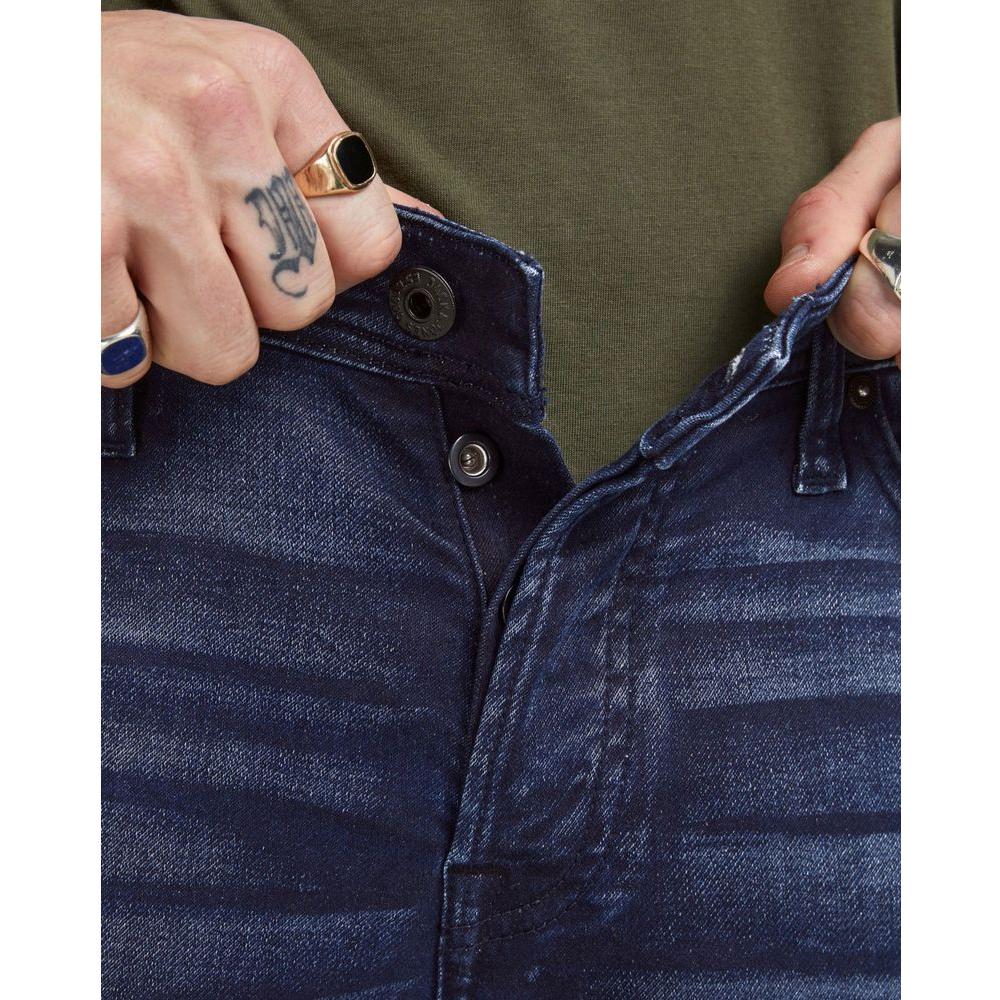 Close-up of person wearing Jack Jones blue cotton jeans, highlighting button closure and denim texture.