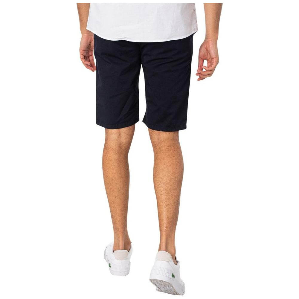 Back view of Lyle & Scott blue men's Bermuda shorts, 97% cotton, from Fall/Winter collection, worn with white sneakers.