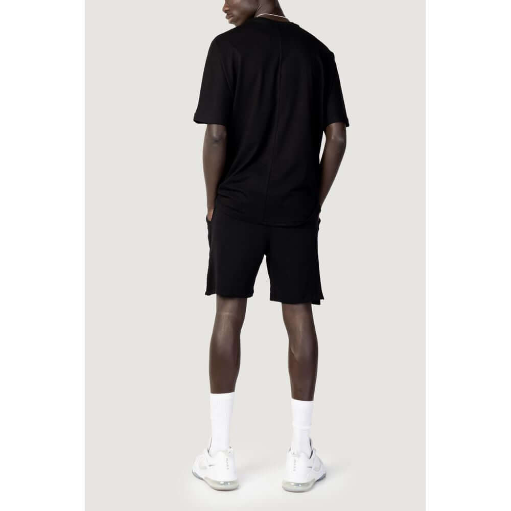 Back view of a man wearing a Hydra Clothing black cotton short sweatsuit, part of the men's spring/summer collection.