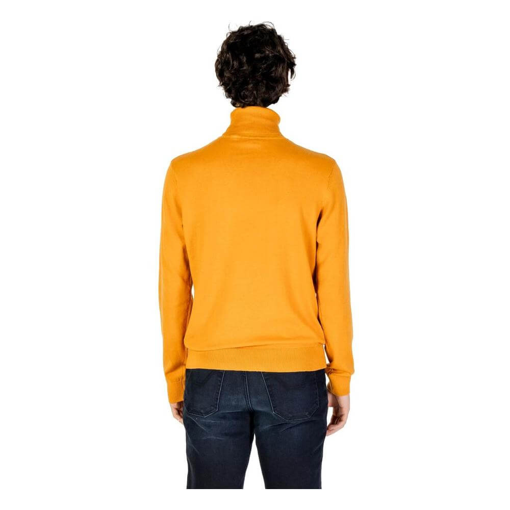 Back view of a man wearing a U.S. POLO ASSN. orange cotton turtleneck sweater, highlighting the elegant and comfortable design.