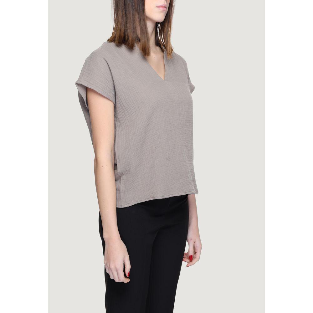 Woman wearing Jacqueline De Yong gray short sleeve cotton blouse, showcasing V-neck design and 80% cotton, 20% recycled cotton composition.