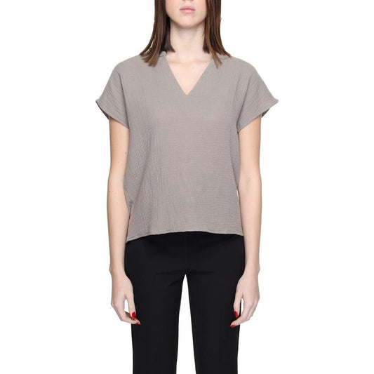 Woman wearing Jacqueline De Yong gray cotton short sleeve blouse, 80% cotton, 20% recycled cotton, eco-friendly fashion.